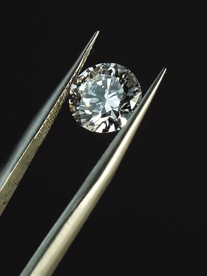 A finished round life diamond, held in tweezers
